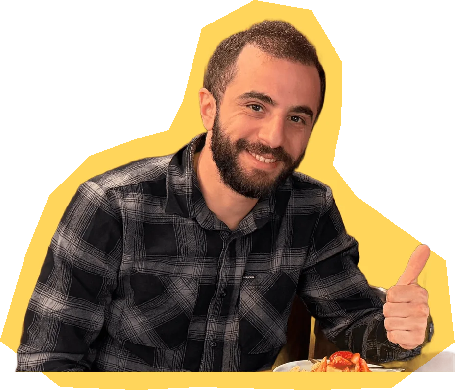Tomer Uzan at a table, smiling, in a checked shirt.